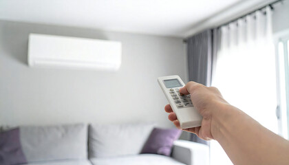 エアコンのリモコンを持つ手。快適な部屋の背景イメージ。Hand holding air conditioner remote control. Comfortable room background image.