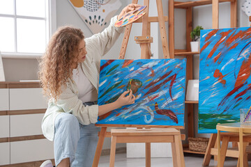Female artist painting on canvas in workshop
