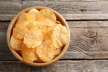 Tasty potato chips in bowl on wooden table, top view. Space for text