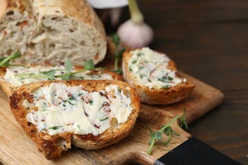 Tasty bread with garlic, herbs and oil on wooden table, closeup