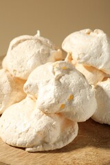 Delicious homemade meringue cookies on wooden table against beige background, closeup