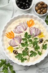 Raw focaccia with vegetables and olives on white marble table, flat lay
