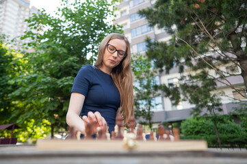 Caucasian woman playing chess outdoors.