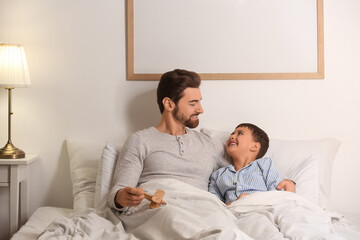 Father with toy plane and his little son lying in bedroom