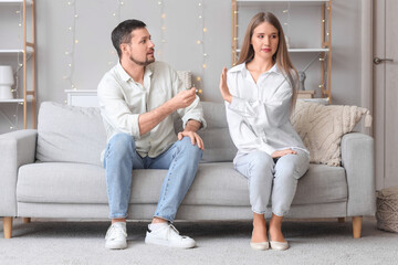 Young woman rejecting marriage proposal from her boyfriend on sofa at home