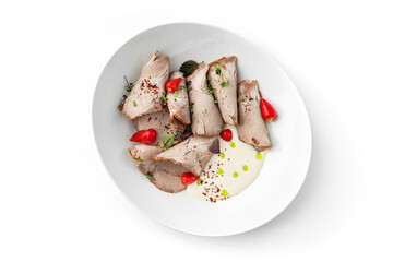 Sliced roast beef on white plate with cherry tomatoes and creamy sauce, garnished with fresh herbs. Healthy food, close up, top view
