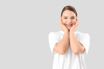 Fototapeta premium Young woman with dental braces smiling on light background
