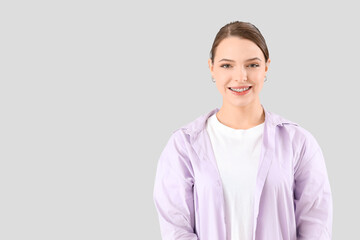 Young woman with dental braces smiling on light background