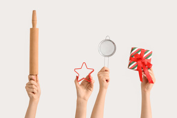 Female hands holding sieve with rolling pin, Christmas gift and cookie cutter on white background