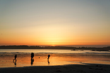 夕焼けに包まれた海辺で遊ぶ人々の姿