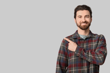 Young man pointing at something on light background