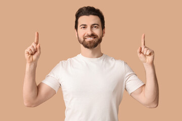 Young man pointing up on beige background