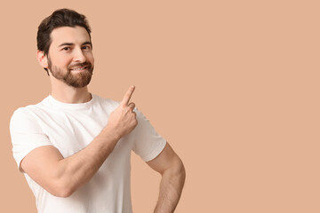 Young man pointing up on beige background