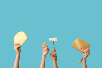 Female hands with cosmetic bags, tampon and flower on blue background