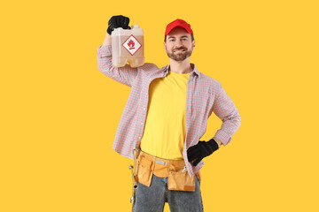 Male mechanic with canister on yellow background