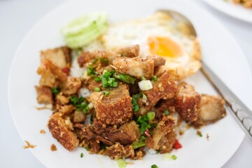 A plate of crispy pork belly stir fried with holy basil (kra pao moo grob), white rice and a fried egg at a street food stall at Soi 20 - Silom, Bangkok, Thailand