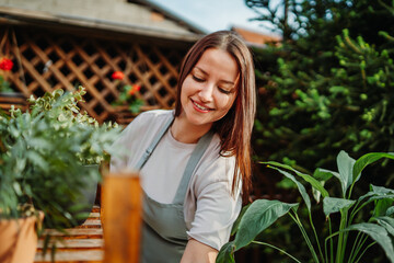 Young woman taking care of plants with water can and mister	
