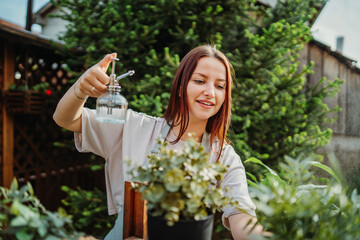 Fototapeta premium Young woman taking care of plants with water can and mister 