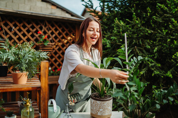 Young woman taking care of plants with water can and mister	
