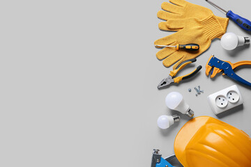 Hardhat, light bulbs and construction tools on grey background