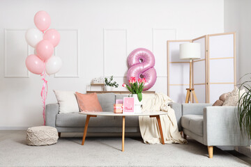 Interior of living room decorated for Women's Day with sofas, table and balloons