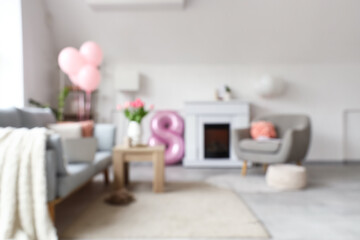 Blurred view of light living room decorated for Women's Day with sofa, armchair and fireplace