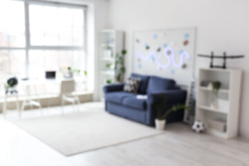 Blurred view of teenager's room with blue sofa, pin board and workplace