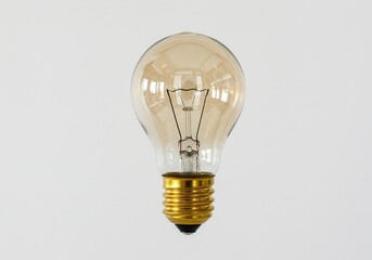 Classic light bulb with gold base against white background shows filament details