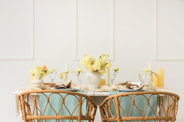 Beautiful table setting with narcissus flowers and candles in light room