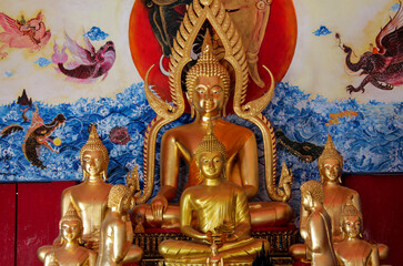 Obraz premium Buddha gold statue in a Buddhist temple Wat in Thailand. Golden Statue of Gautama Buddha sacred relic of Thai Buddhism religion. Decoration of thai wat with beautiful golden figure of sitting Buddha