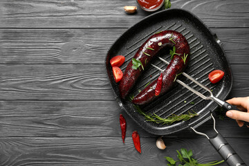 Grill pan with tasty blood sausage on dark wooden background