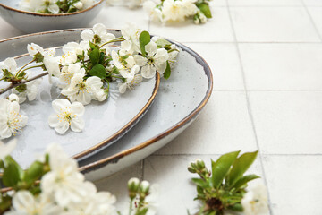 Clean plates with blooming branches on white tile background, closeup