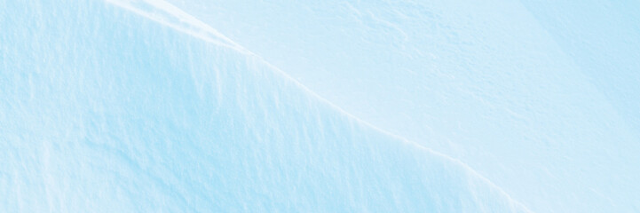 Wide panoramic winter background with snowy ground. Natural snow texture. Wind sculpted patterns on snow surface. Closeup top view with copy space.