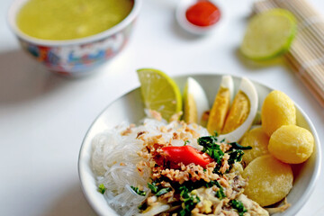 A steaming bowl of soto daging ayam, a traditional Indonesian culinary chicken soup stew with glazed noodles 