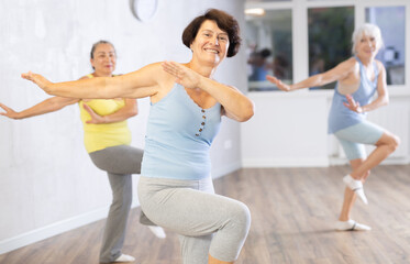 Joyful old ladies training dance positions in light room during workout session