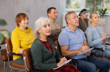 Older male and female students listening to lecture in university
