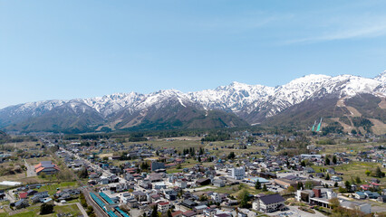 Panoramic aerial view rural town nestled in a valley with snow-capped mountains towering in the background at Hakuba Mountain Nagano, Japan.