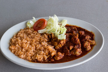 A delectable plate featuring flavorful asado de puerco cooked in rich sauce served with rice and fresh vegetables, ideal for those who appreciate hearty and wholesome home-cooked meals.