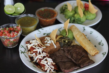 A vibrant Mexican tampiqueña platter showcasing an assortment of delicious dishes including grilled meat, tacos, sauces, and garnishes, perfect for showcasing culinary culture.