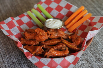A delicious platter of crispy chicken wings artfully arranged with fresh carrot and celery sticks, ideal for gatherings, parties, or a shared experience with friends.
