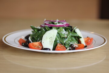 A fresh and vibrant salad composed of mixed greens, tomatoes, cucumbers, and onions, topped with cheese, embodying healthy eating and colorful mini-explosions of flavor.