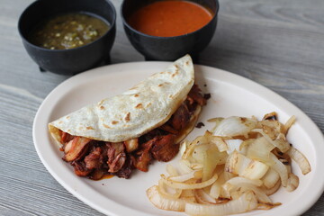 A delicious al pastor taco featuring grilled pork, accompanied by fresh salsas and grilled onions, offering a delightfully savory taste that represents authentic street food culture.