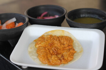 A soft tortilla filled with spicy shredded chicken, served with traditional pickled vegetables and vibrant sauces for an authentic taste experience.