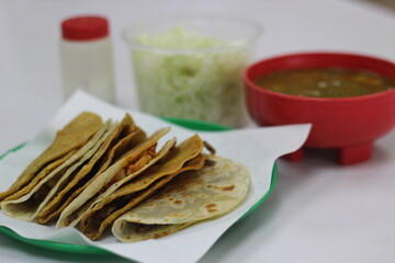 A vibrant plate of tacos is served with fresh lettuce, and a bowl of salsa on the side, showcasing traditional culinary delights in a well-presented manner.