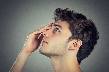 Close-up profile view of a young man looking upward thoughtfully.
