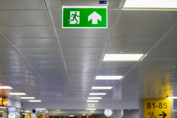 Green emergency exit sign on the ceiling of the airport,also ideal for airport safety practices