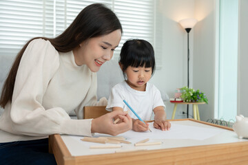 Fototapeta premium Happy Asia mother play and learn drawing for little girl. Funny family is happy and excited in the house. Mother and daughter having fun spending time together. Holiday, Activity