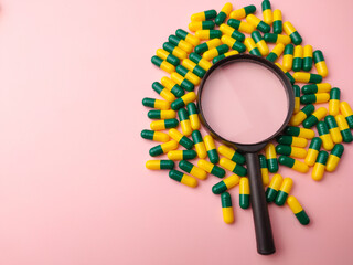 Medicine pill and magnifying glass on a pink background with copy and text space