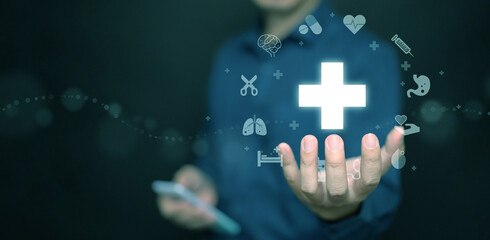 Healthcare and health insurance concept. A man with his smartphone holding health cross symbol with icons