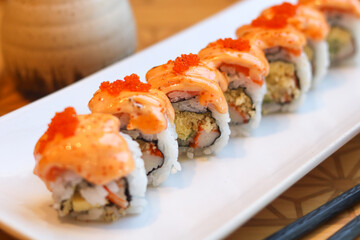 Close-up of salmon mentai sushi roll topped with creamy mentai sauce and fish roe. A rich and savory fusion favorite.